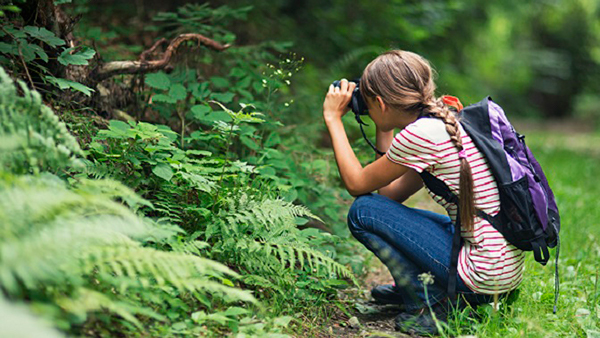 Young girl taking a outdoor picture with her camera. 