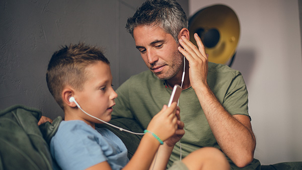 Father and son listening music on the phone. 